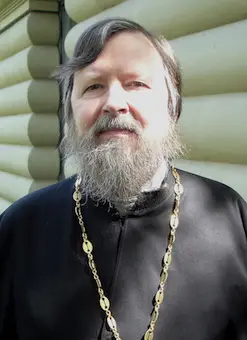 Erzpriester Dr. Peter Plank in schwarzem Priestergewand mit der Kette des Brustkreuzes, vor einer hellen Holzwand