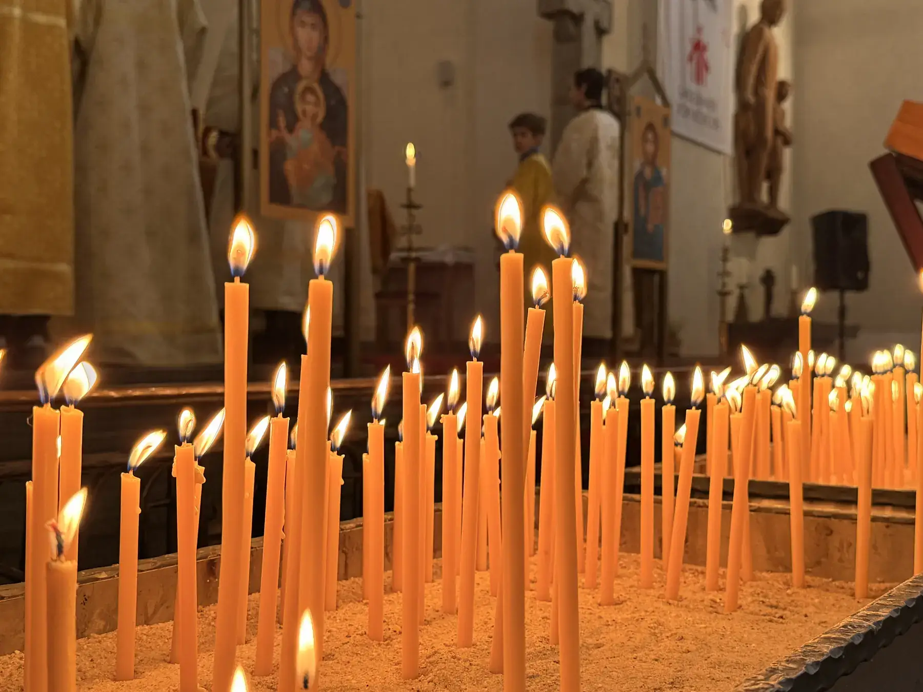 Viele dünne Wachskerzen brennen dicht nebeneinander in der Don-Bosco-Kirche, dahinter weiches Licht