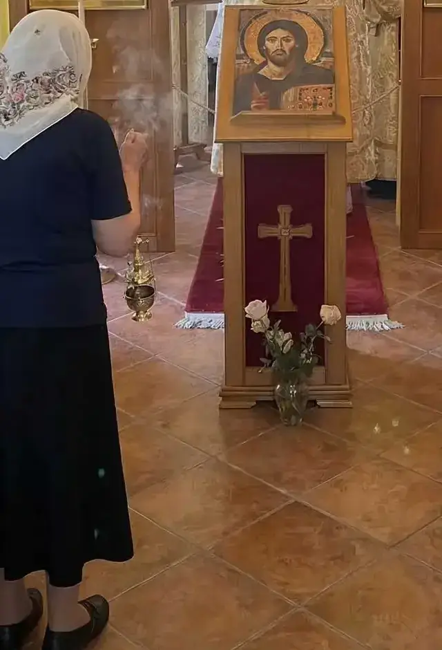 Gottesdienst im Zeller Torhaus in Würzburg, Blick von hinten: eine Frau mit weißem, geblümtem Kopftuch und langem schwarzem Rock, daneben das Pult mit der Christusikone